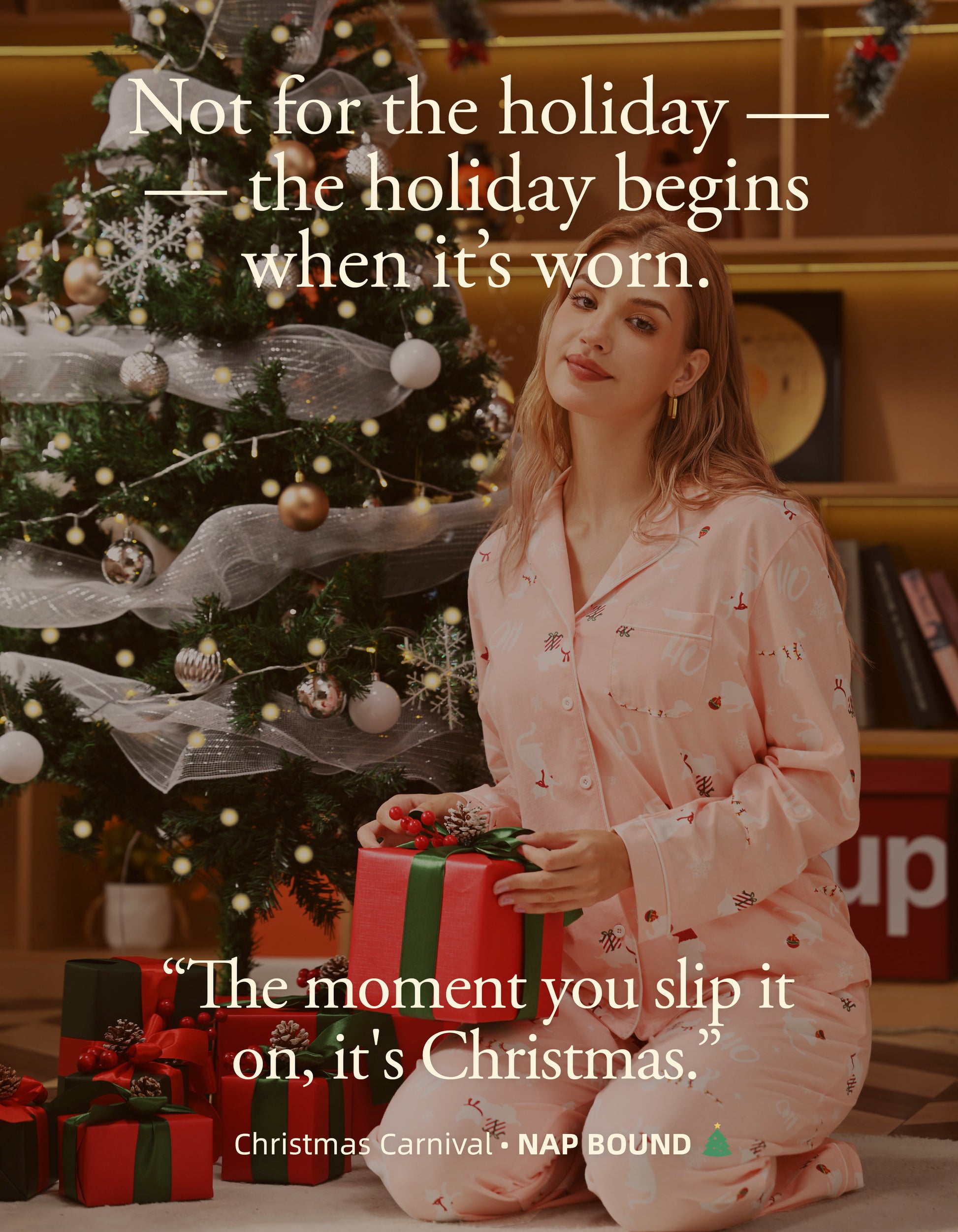 Woman wearing pink Christmas knit cotton pajamas holding gift beside Christmas tree