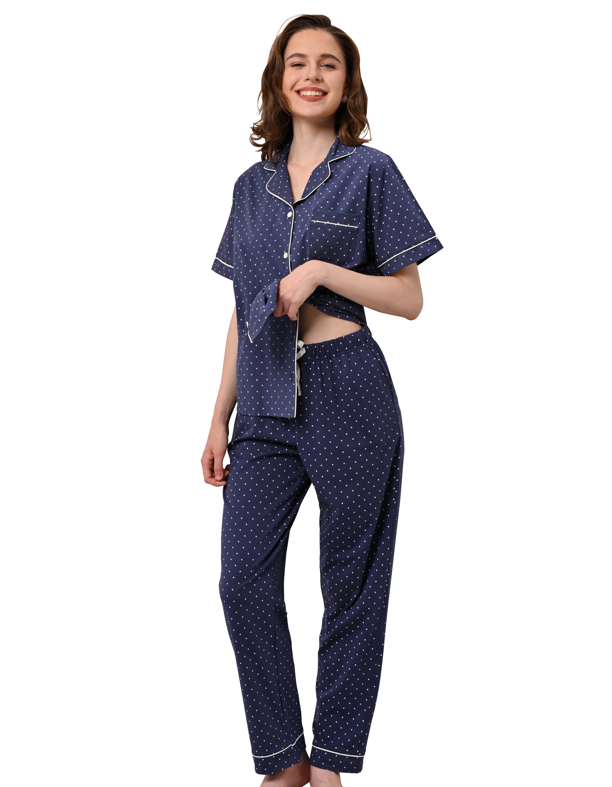 Women wearing navy polka dot cotton pajama set with short sleeve button-down top and long pants on white background